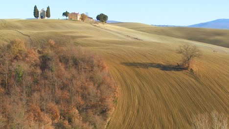 A-beautiful-farmhouse-and-church-in-the-distance-in-Tuscany-Italy-1