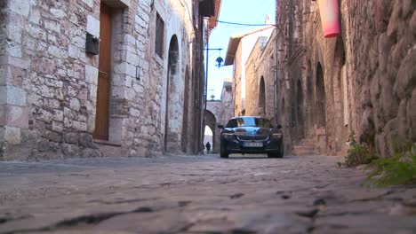 A-new-BMW-drives-down-a-narrow-alley-in-Assisi-Italy