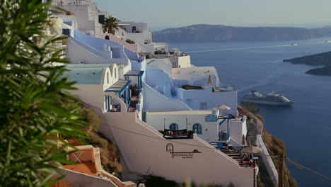 White-houses-line-the-hillsides-of-the-Greek-Island-of-Santorini-with-a-cruise-ship-in-the-distance