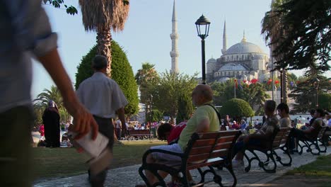 Los-Peatones-Caminan-Y-Se-Sientan-En-Bancos-Cerca-De-La-Mezquita-Azul-En-Estambul,-Turquía