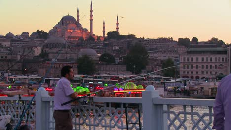 Pescador-Y-Coloridos-Barcos-Al-Atardecer-En-Frente-De-Una-Mezquita-En-Estambul,-Turquía