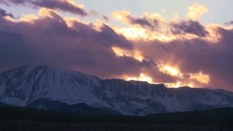 Zeitraffer-Der-Schneebedeckten-Berge-Der-Sierra-Nevada-Mit-Der-Sonne,-Die-Durch-Die-Wolken-Scheint