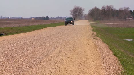 A-pickup-truck-drives-on-a-dirt-road-through-Midwest-farmland