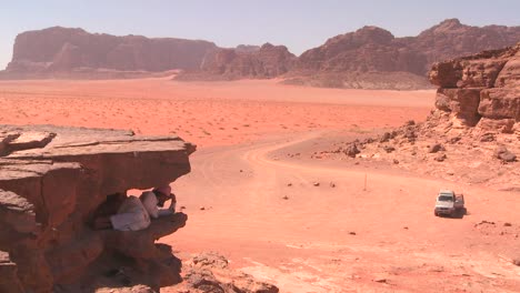 An-Arab-man-sleeps-under-a-steep-cliff-overlooking-the-Saudi-desert-sands-of-Wadi-Rum-Jordan