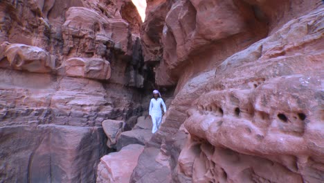 Un-Hombre-árabe-Camina-A-Lo-Largo-De-Una-Cornisa-Estrecha-En-Un-Cañón-En-El-Desierto-De-Arabia-Saudita-De-Wadi-Rum-Jordania
