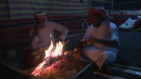 Two-Bedouin-men-sit-in-a-tent-in-front-of-a-campfire-in-the-desert-and-laugh-and-talk