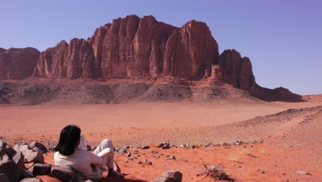Ein-Araber-In-Traditioneller-Kleidung-Sitzt-Und-Betrachtet-Die-Wüste-Von-Wadi-Rum-Jordan