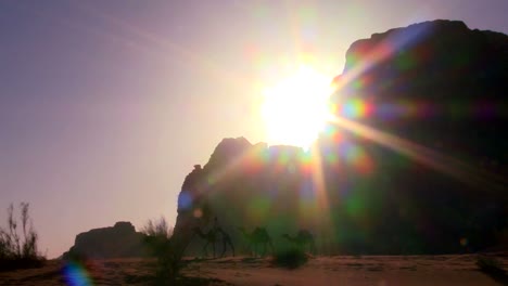 Schwenken-Sie-über-Einen-Sonnenaufgang-In-Der-Wüste,-Während-Ein-Kamelzug-Die-Saudische-Wüste-Im-Wadi-Rum-Jordanien-Durchquert