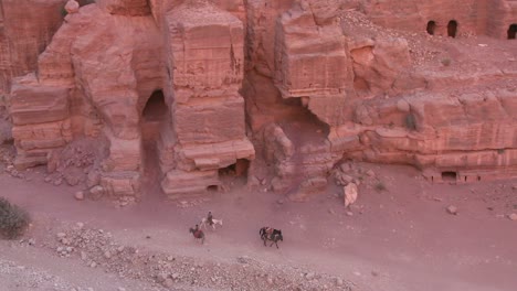 Hohe-Betrachtungswinkel-Von-Sandsteingräbern-Und-Menschen,-Die-Esel-In-Den-Alten-Nabatäerruinen-Von-Petra-Jordanien-Reiten
