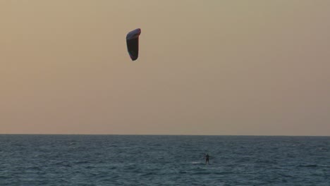 A-windsurfer-moves-along-a-coastline-at-dusk