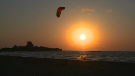 A-windsurfer-moves-along-a-coastline-at-sunset