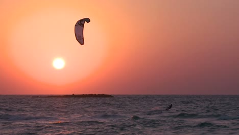 A-windsurfer-moves-along-a-coastline-at-sunset-3