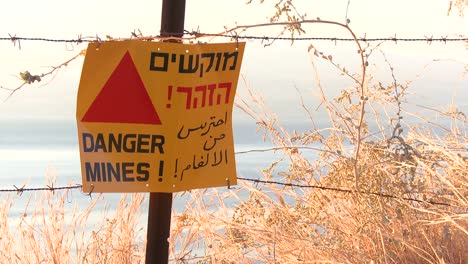 A-sign-warns-in-English-Arabic-and-Hebrew-that-mines-are-nearby-along-the-Israel-border-with-Syria