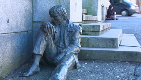 Ein-Obdachloser-Sitzt-In-Der-Nähe-Einer-Statue,-Die-Einen-Obdachlosen-Auf-Den-Straßen-Von-Norwegen-Darstellt