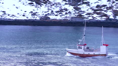 A-fishing-boat-heads-through-fjords-in-the-Arctic-Lofoten-Islands-Norway