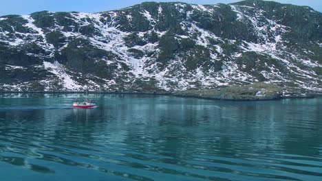 A-fishing-boat-heads-through-fjords-in-the-Arctic-on-glassy-green-water-in-the-Lofoten-Islands-Norway-1