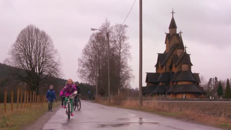 Children-play-in-front-of-an-old-wooden-stave-church-in-Norway