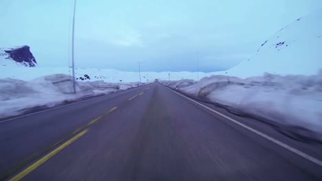 POV-shot-of-a-car-traveling-at-high-speed-along-a-mountain-road-with-ice-and-snow