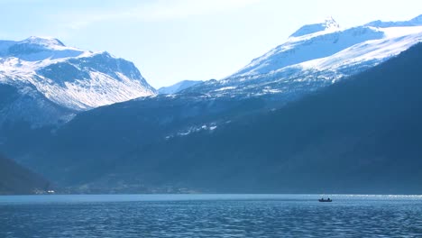 Beautiful-wide-shot-of-the-fjords-of-Norway-with-people-in-a-canoe-distant