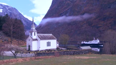 A-ferry-boat-passes-a-pretty-church-along-the-shore-in-Norway