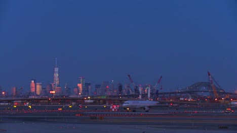 Planes-taxi-at-Newark-airport-at-dusk-with-the-Manhattan-skyline-glowing-in-the-background
