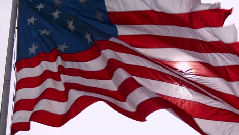 An-American-flag-waves-in-slow-motion-with-the-sun-behind-1