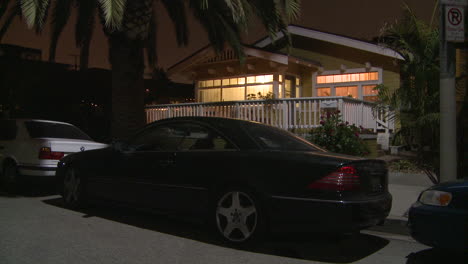 A-black-Mercedes-is-parked-in-from-of-a-quaint-wooden-house-in-Florida-or-California-at-night