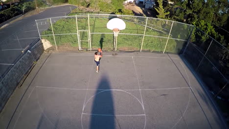 A-birds-eye-aerial-over-a-basketball-player-shooting-a-layup-on-an-outdoor-court-1