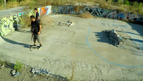 Toma-Aérea-De-Adolescentes-En-Patineta-En-La-Base-Cubierta-De-Graffiti-De-Un-Edificio-Abandonado-4