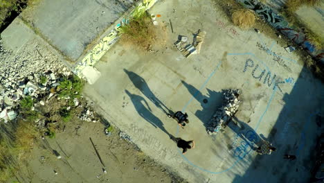 Toma-Aérea-De-Muchachos-Adolescentes-En-Patineta-En-Los-Cimientos-Cubiertos-De-Graffiti-De-Un-Edificio-Abandonado-5