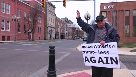 A-man-holds-up-an-antiTrump-rally-sign-saying-Make-America-Trump-less-Again-on-an-American-street-corner-1