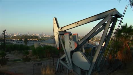 An-oil-well-pumps-oil-with-a-sprawling-suburban-landscape-behind