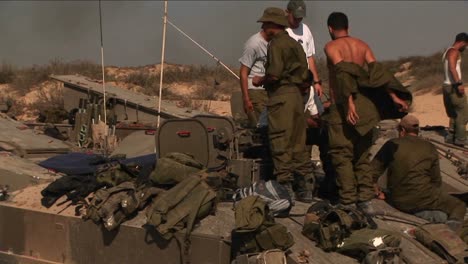 Off-duty-Israeli-soldiers-stand-on-top-of-a-tank-during-a-conflict-in-a-border-region