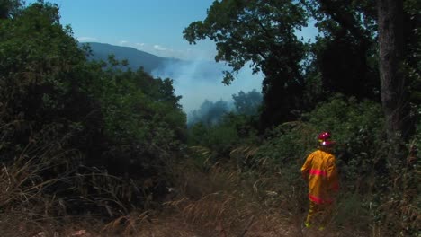 A-firefighter-walks-quickly-down-a-dirt-road-approaching-a-wildfire