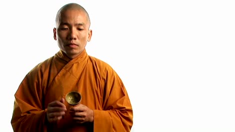 A-Buddhist-monk-wearing-an-orange-robe-taps-a-bell-with-a-small-stick