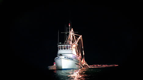 A-fishing-boat-is-illuminated-on-the-water-at-night