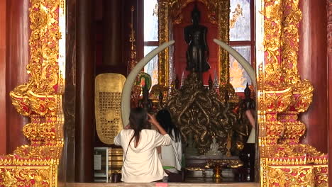 A-young-woman-enters-a-Buddhist-temple-in-Thailand-and-sits-to-and-begins-to-pray