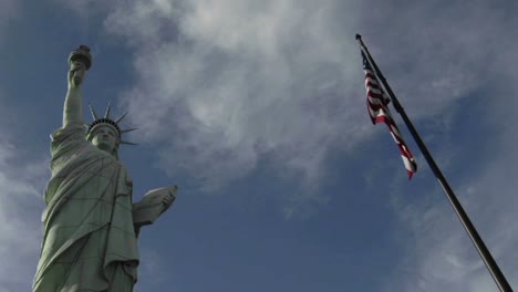 A-time-lapse-of-clouds-moving-over-the-Statue-of-Liberty-and-an-American-flag