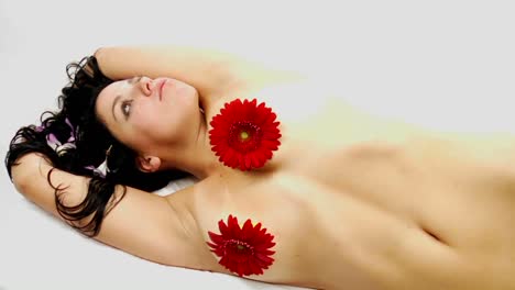 A-woman-lying-on-her-side-wears-flowers-to-cover-her-chest