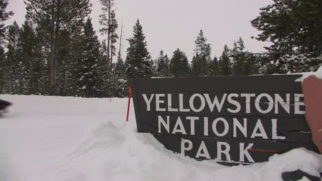 The-entrance-to-Yellowstone-National-Park-in-winter-with-snowmobiles-passing