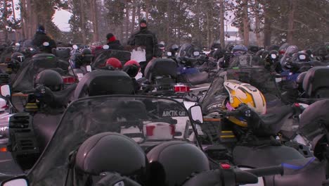 Many-snowmobiles-are-lined-up-in-a-snowmobile-parking-lot