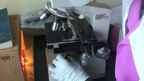 A-technician-examines-a-specimen-through-a-microscope