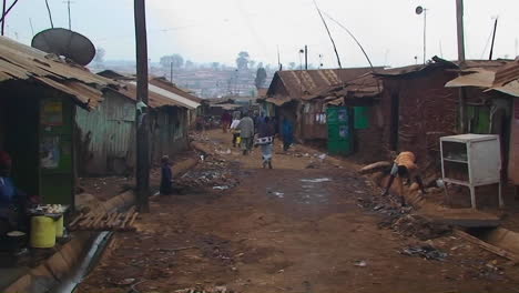 People-walk-down-a-dirty-street-in-a-shanty-town