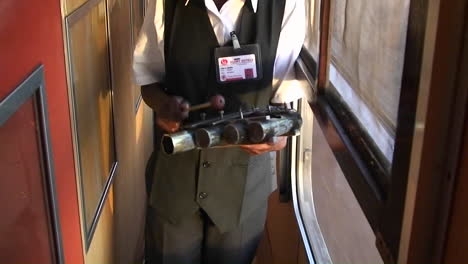 An-attendant-on-a-train-walks-up-and-down-the-aisle-ringing-a-bell