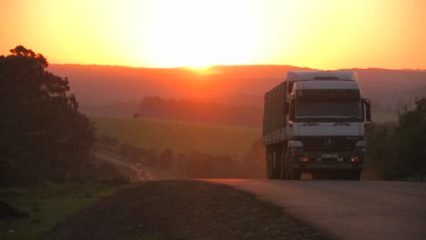 A-truck-travels-down-a-rural-highway-near-sunset