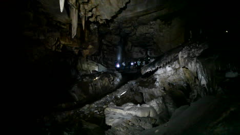 People-explore-a-dark-cave-with-flashlights-1