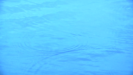 Water-drops-hitting-an-expanse-of-very-blue-water