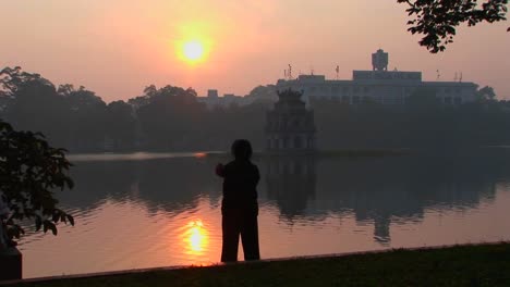 A-woman-practices-tai-chi-in-front-of-a-lake-in-Hanoi-Vietnam