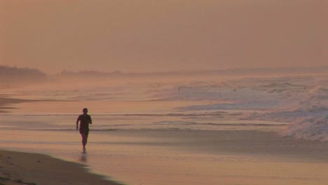 A-man-jogs-along-a-beach-in-silhouette
