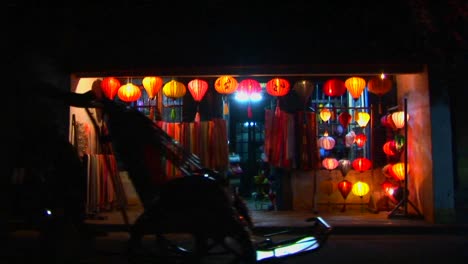 Bicycles-and-rickshaws-pass-a-colorful-lantern-store-at-night-in-Vietnam